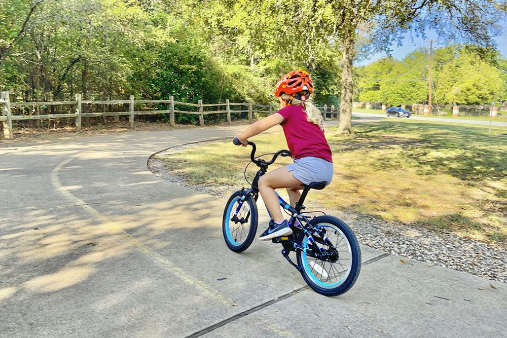 Girl riding Guardian Airos 16 inch bike down paved trail