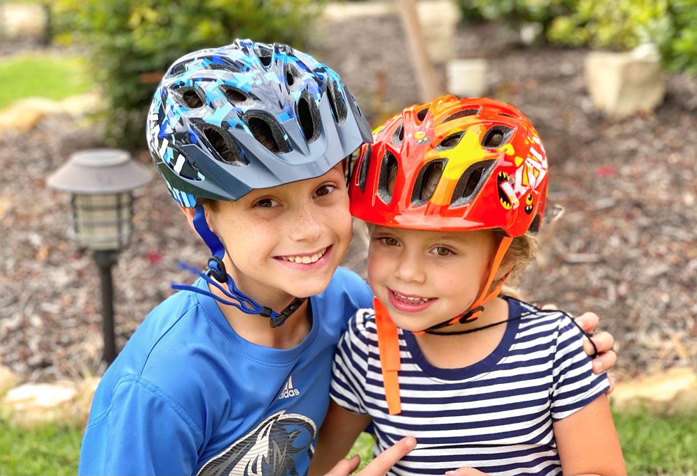 Two kids laughing and wearing the Kali Chakra Youth and Child helmets