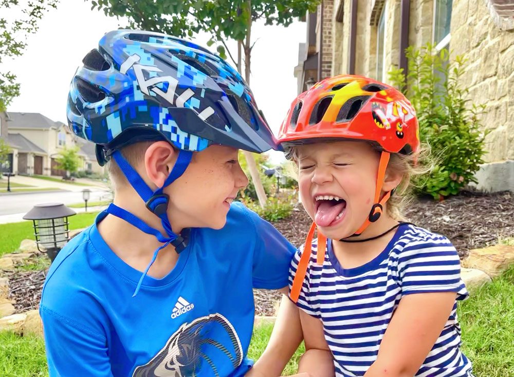 Two kids laughing and wearing the Kali Chakra Youth and Child helmets