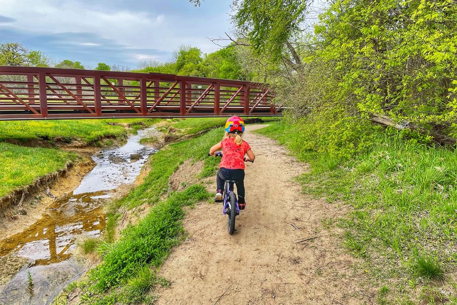 Girl riding Prevelo Alpha Two down a dirt path towards a bridge
