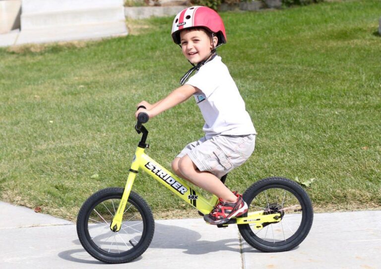 boy riding a yellow strider 14x