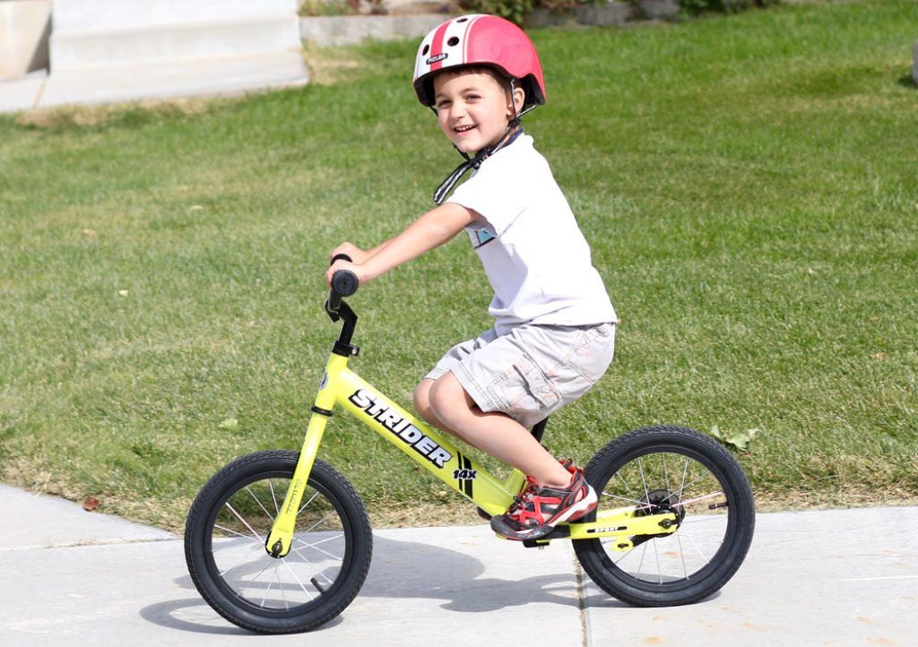 boy riding a yellow strider 14x