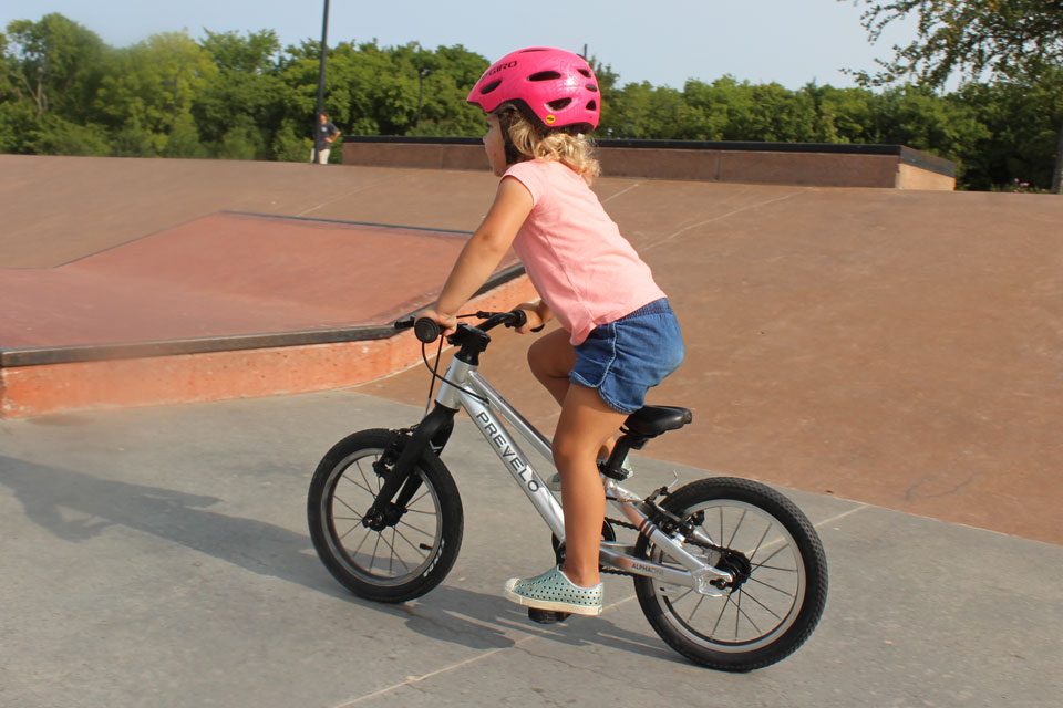 2 year old standing on her pedal, getting out of the saddle on the Prevelo Alpha One 14" kids bike