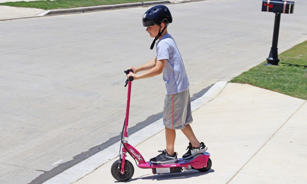 boy riding a pink Razor E100 electric scooter