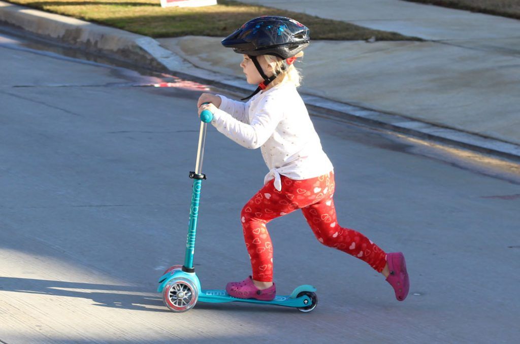 young girl riding a blue micro mini kick scooter