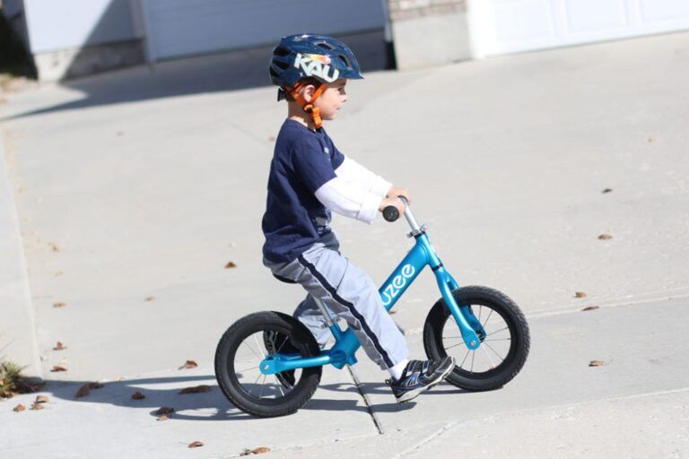 boy riding a blue cruzee balance bike