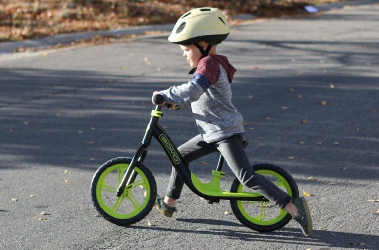 boy riding a green and black gomo balance bike