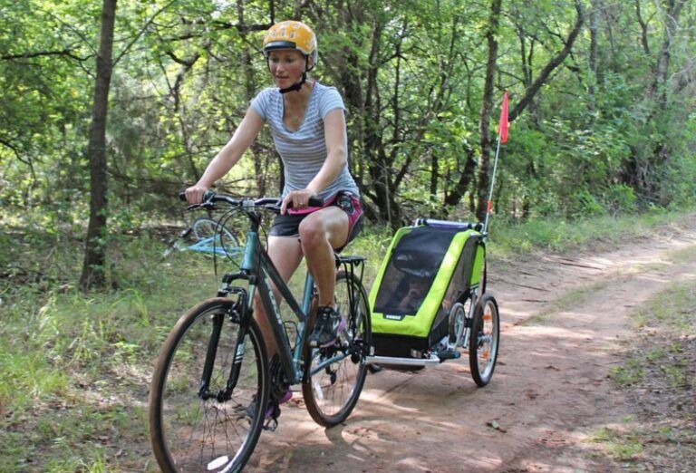 woman pulling the thule cheetah xt trailer behind her bike on a trail