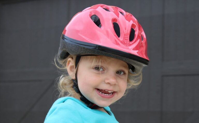 toddler wearing a pink joovy bike helmet