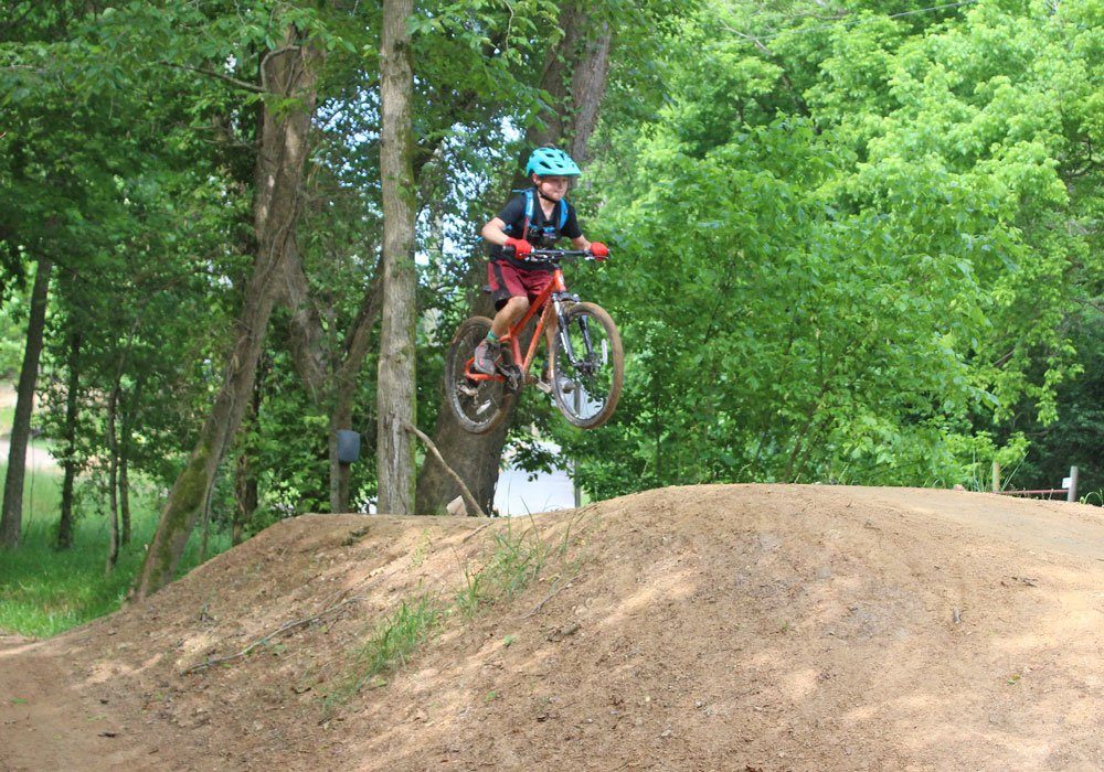 9 year old riding Pello Reyes 24 inch kids bike on trail at Slaughter Pen in Bentonville and catching air on jump