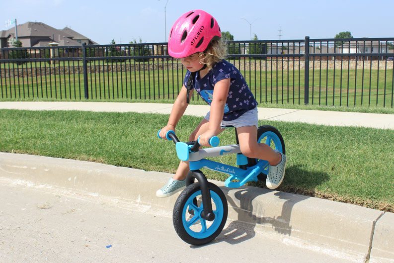 Toddler riding Chillafish balance bike over the curb