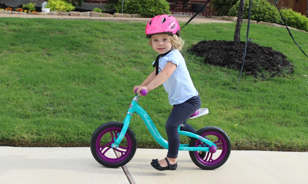 toddler riding a green balance bike