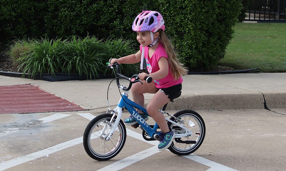 child riding a blue woom 2 bike