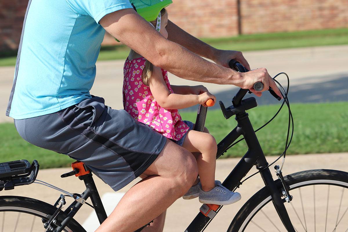 Side shot of dad riding with his daughter on Tyke Toter child bike seat