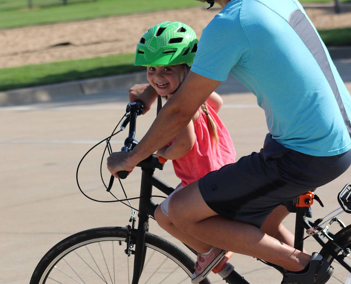 little girl smiling while riding on the Tyke Toter child bike seat