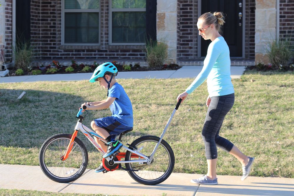 Mom holding the Balance Buddy to help her son learn to pedal his bike