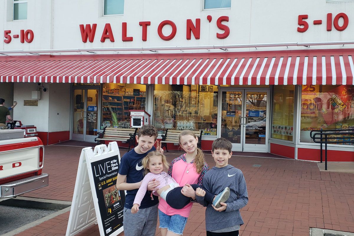 4 kids standing in front of Walton's Five and Dime in Bentonville Arkansas