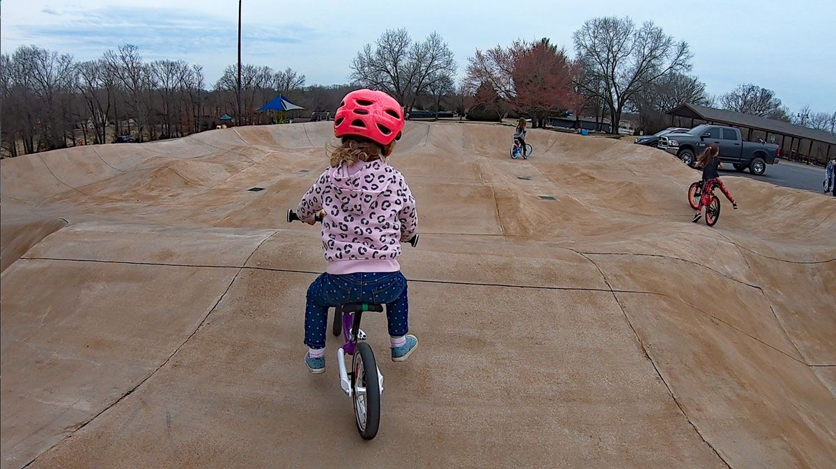 Toddler riding concrete pump track at Metfield Skills Park in Lake Bella Vista Arkansas
