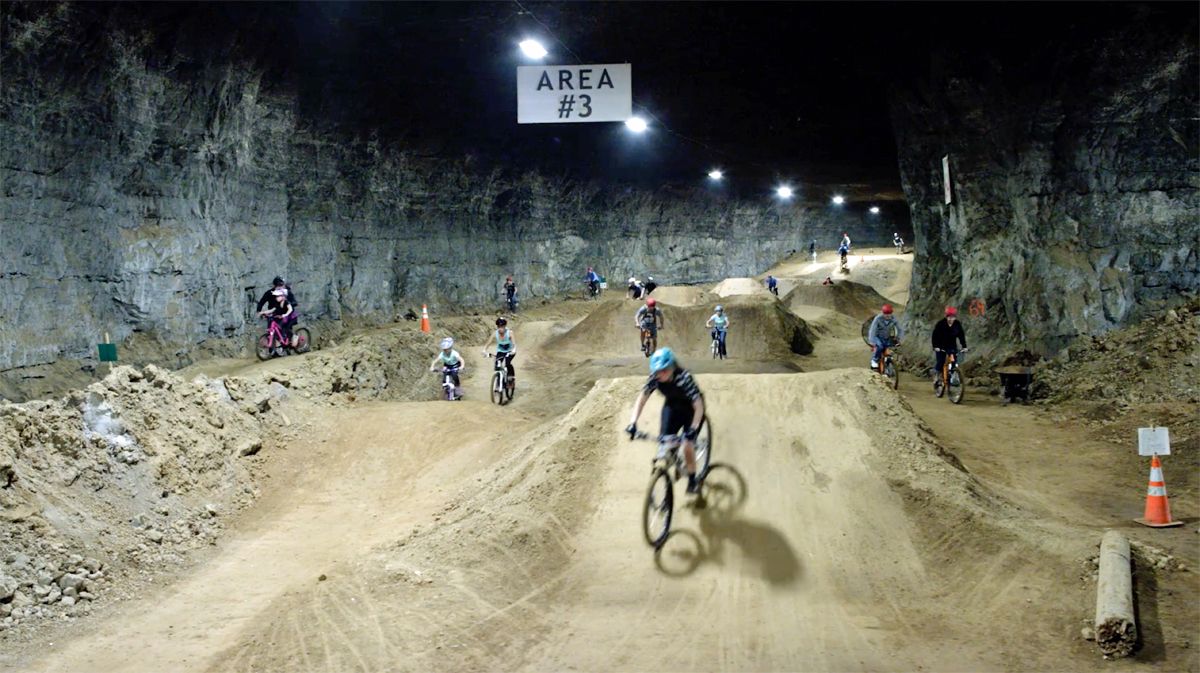 Louisville Mega Cavern Bike Park - many people riding down dirt hills in underground bike park