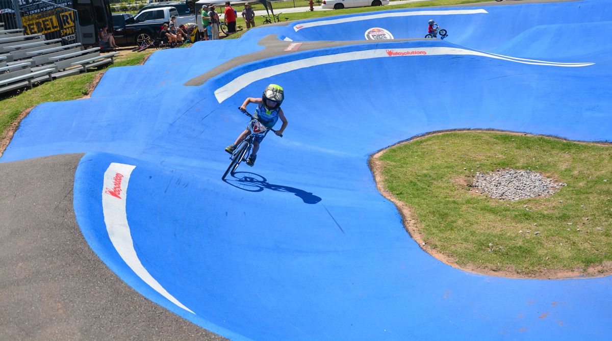 Child riding down blue pump track at OKC Riversport Pump Track