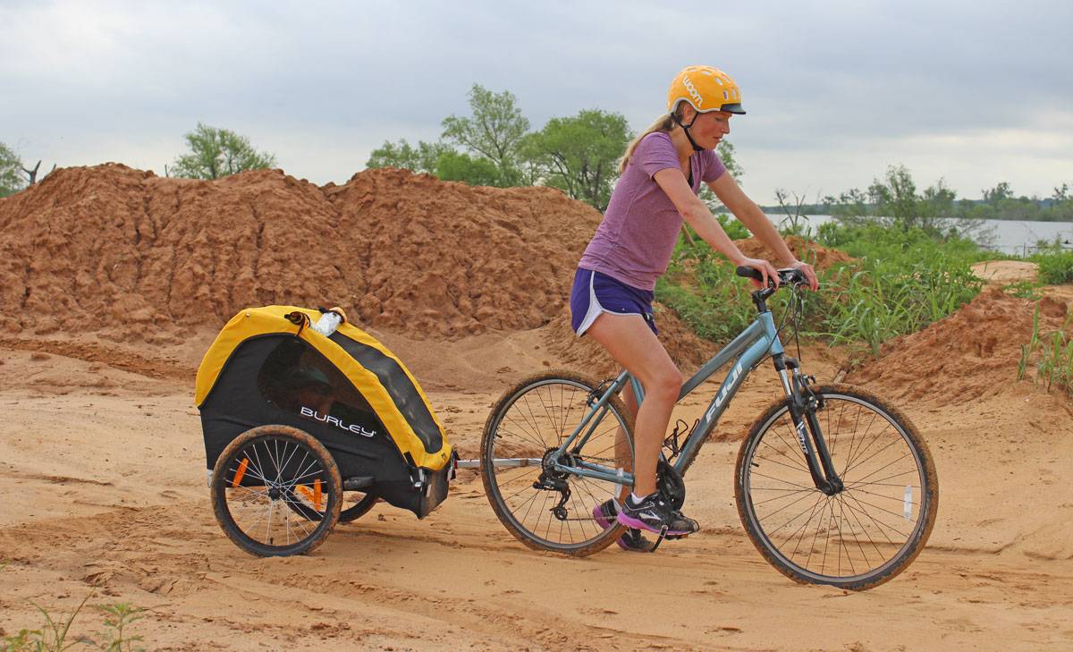Mom pulling Burley Bee bike trailer on sandy trail