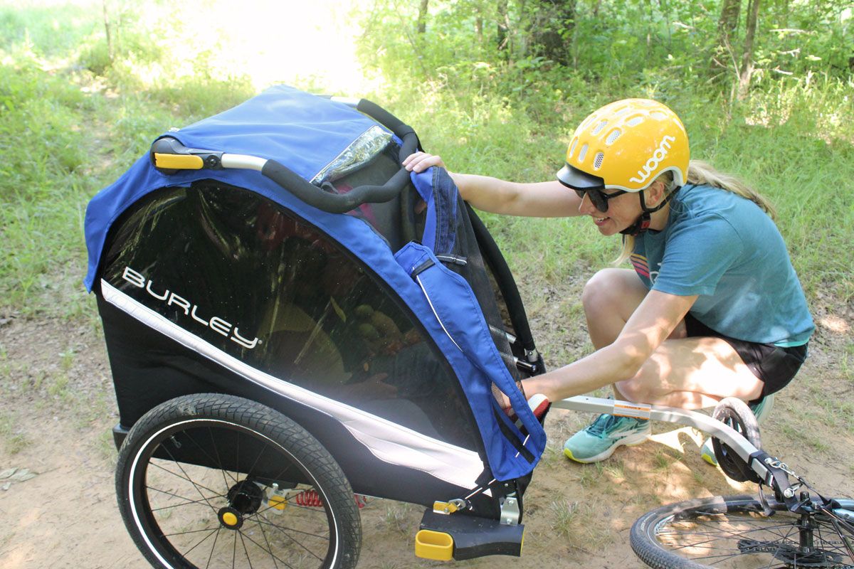Mom opening front cover of Burley D'Lite bike trailer