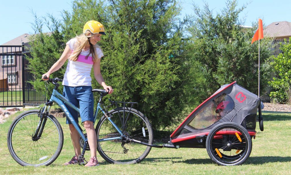 mom pulling their daughter behind her bike in a hamax outback