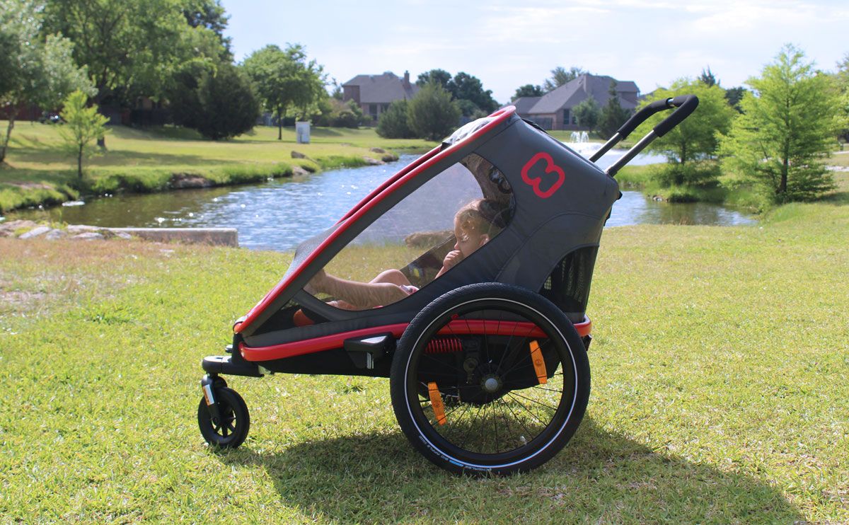 Young girl sitting in Hamax Outback stroller sitting by lake