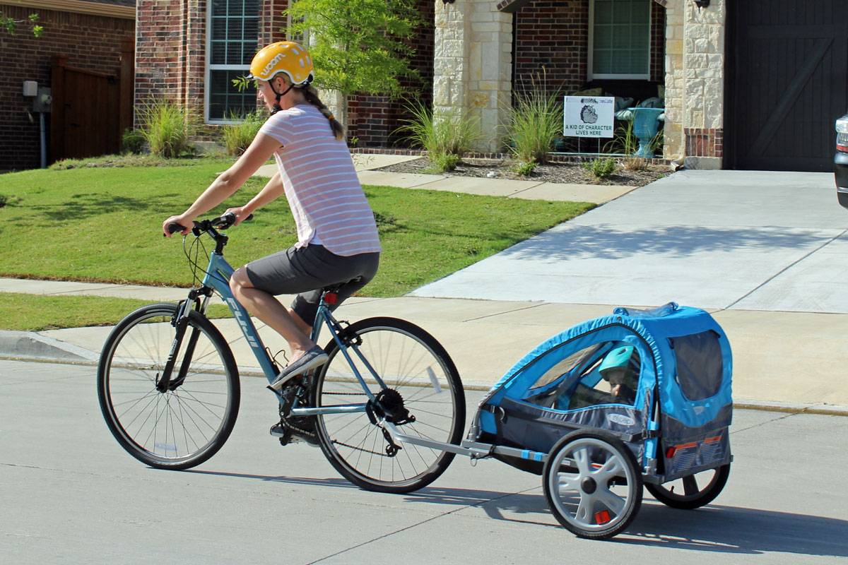 Mom pulling toddler in InStep bike trailer.