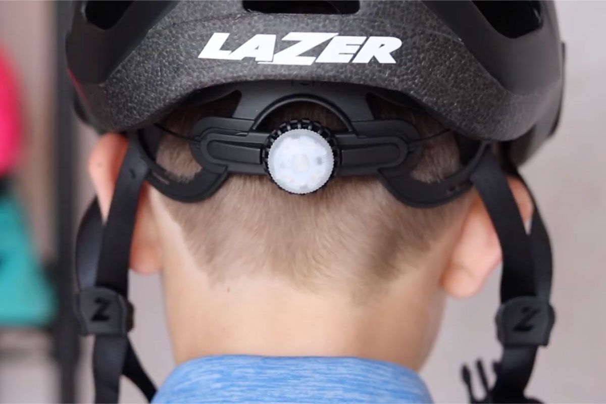 Back of a kid helmet on a child's head showing the dial adjust knob to get the right size