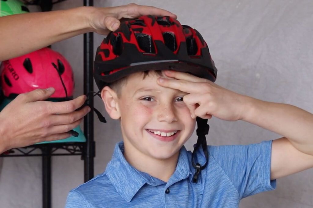 child putting two fingers up to show that his helmet fits properly