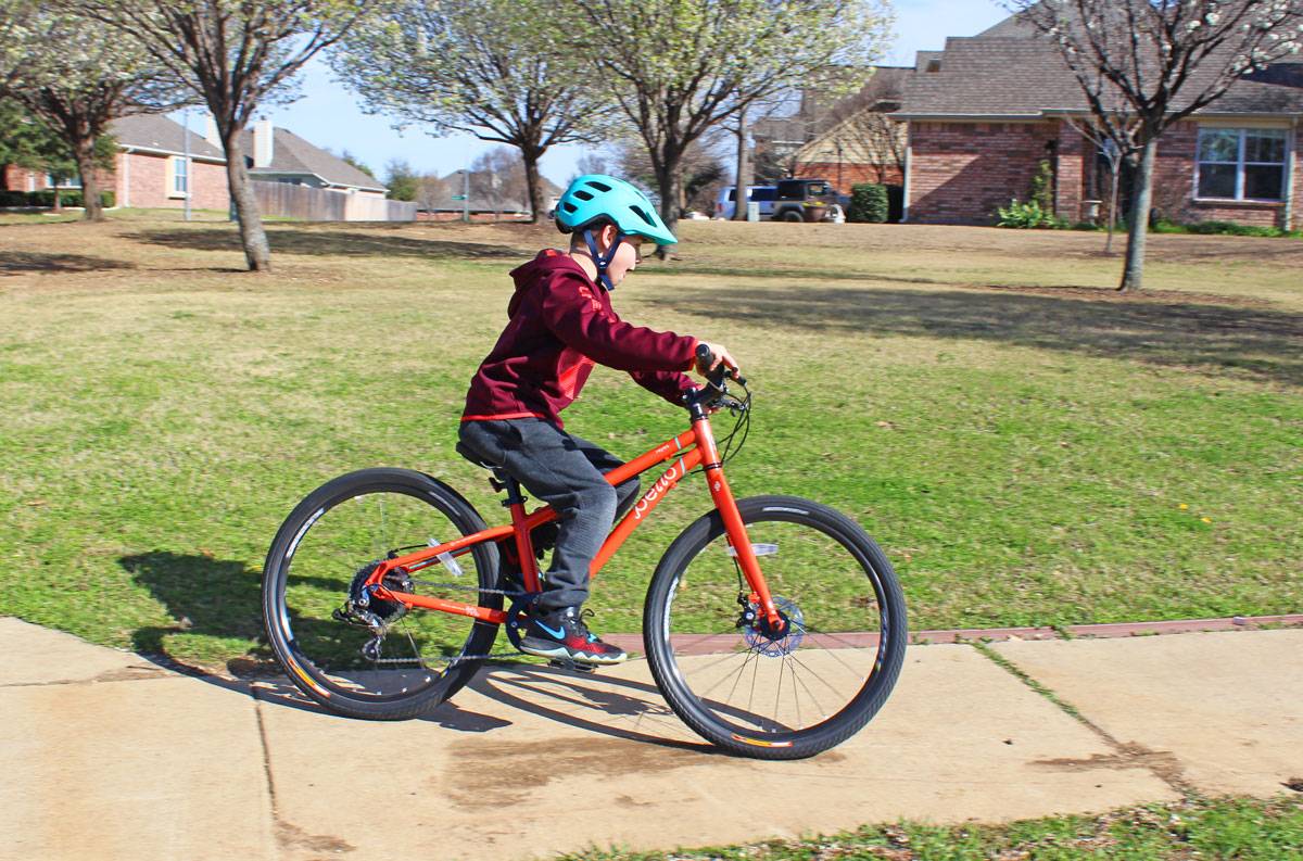 Child riding Pello Reyes on paved neighborhood trail