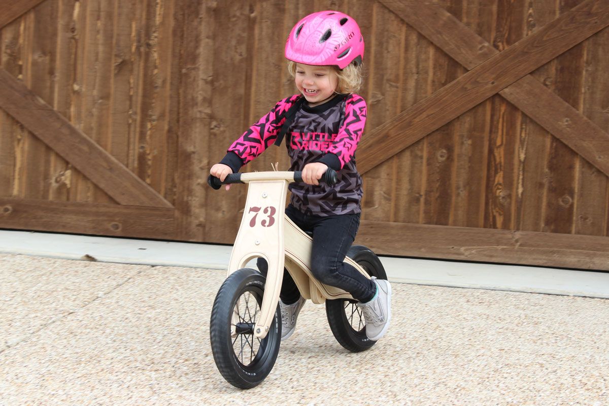 2 year old gliding down driveway on Prince Lionheart wooden balance bike