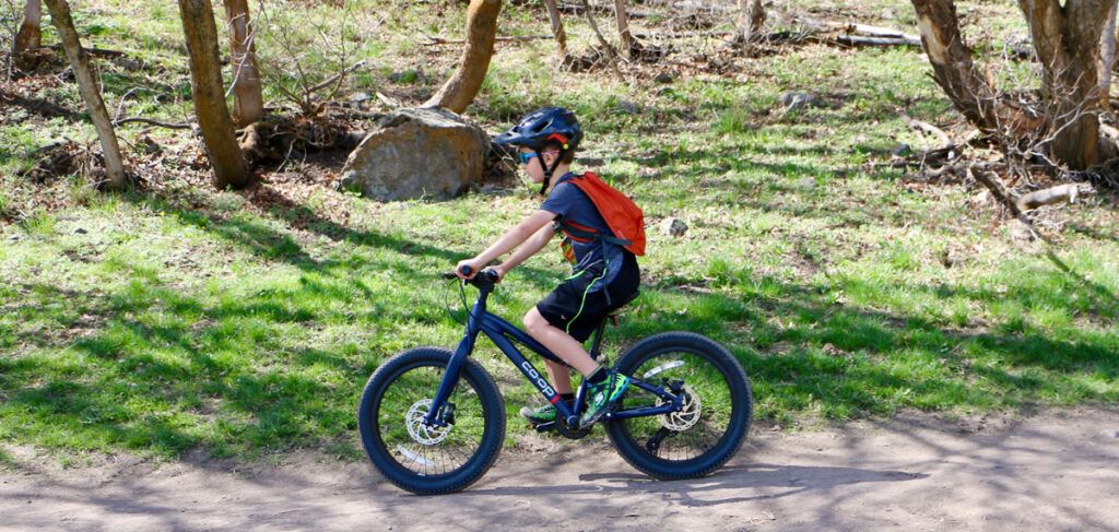 7 year old riding the rei rev co-op plus 20 inch kids bike on a trail