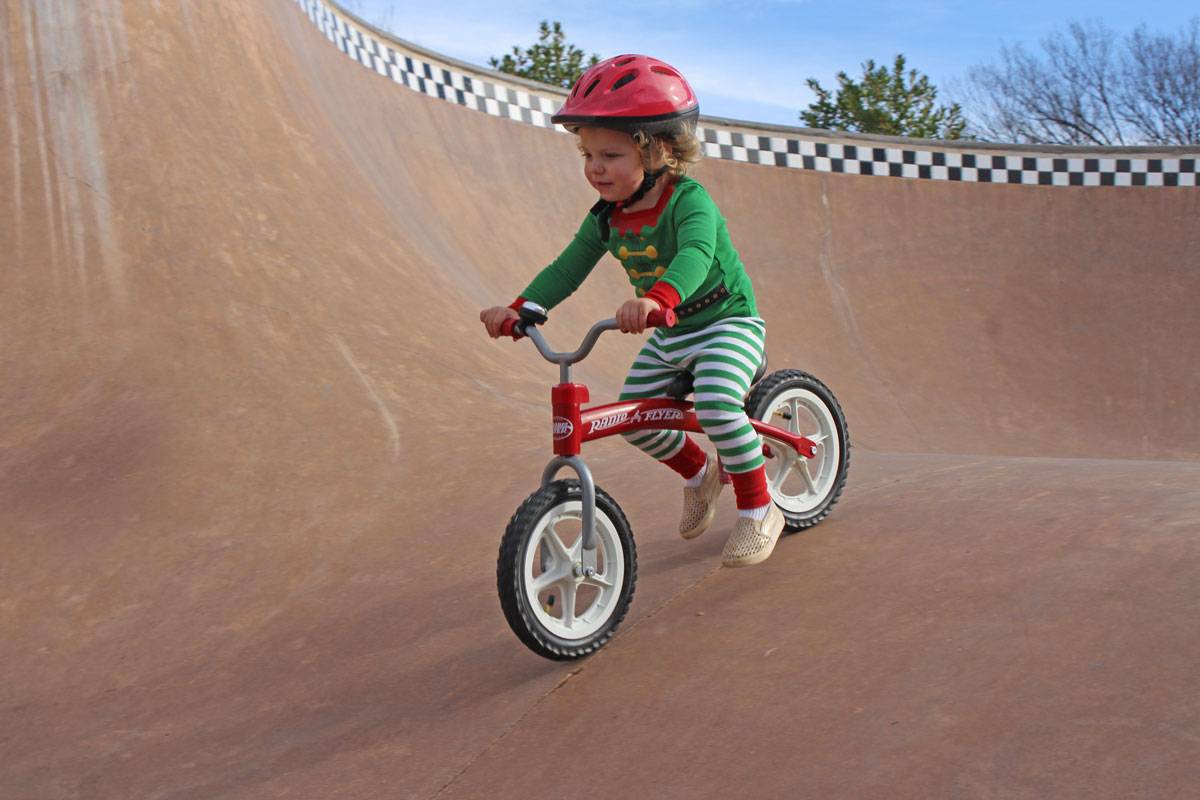 toddler riding Radio Flyer balance bike down the ramp at a skatepark