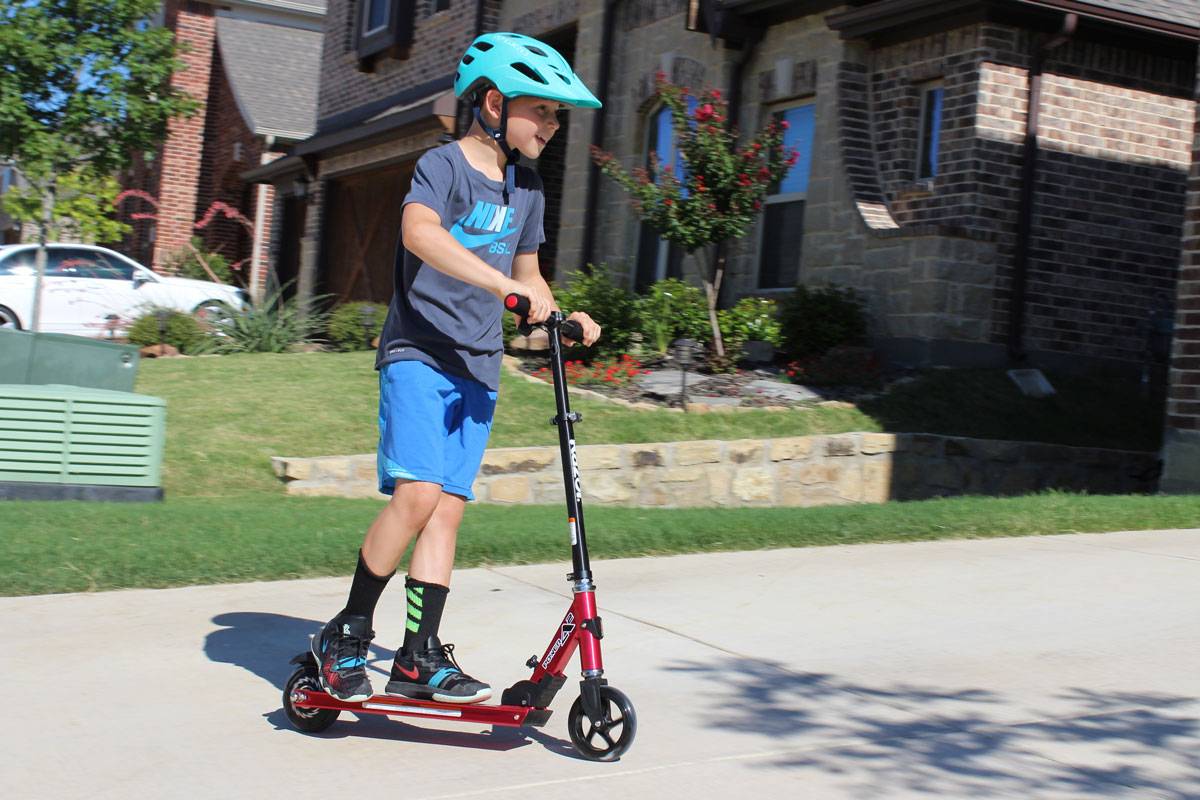 8 year old boy riding Razor Power A2 electric scooter in front of his house
