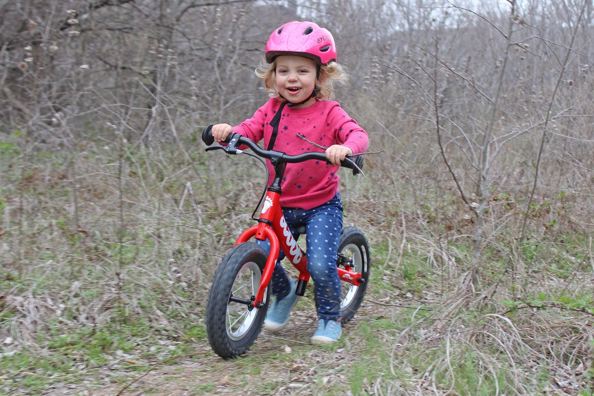 Toddler riding Ridgeback Scoot balance bike through the forest on a trail.