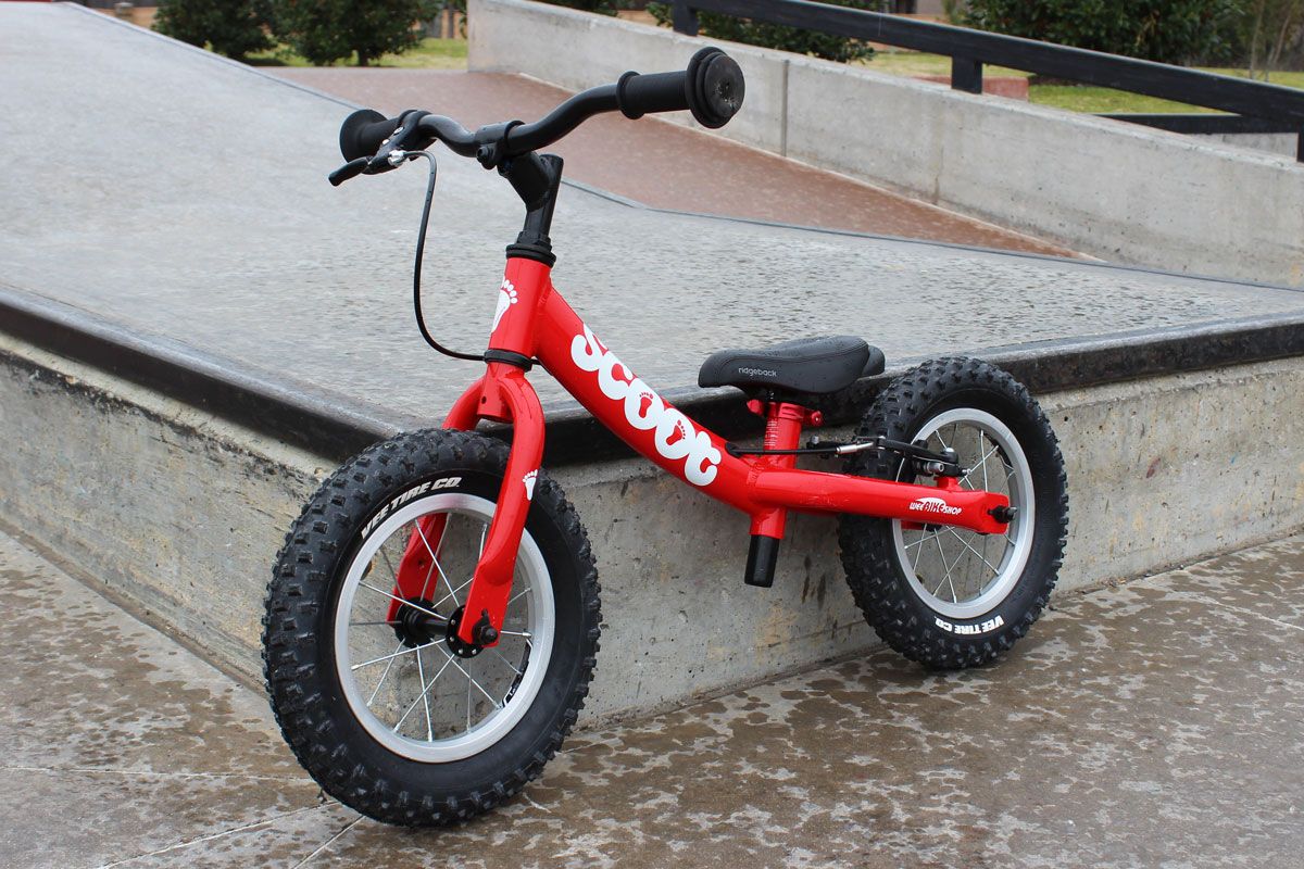 Ridgeback Scoot balance bike in red shown at the skatepark