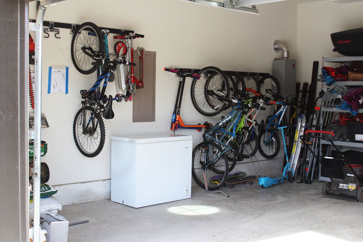 Wide shot of Rubbermaid FastTrack storage system in garage with scooters and bikes hanging from it