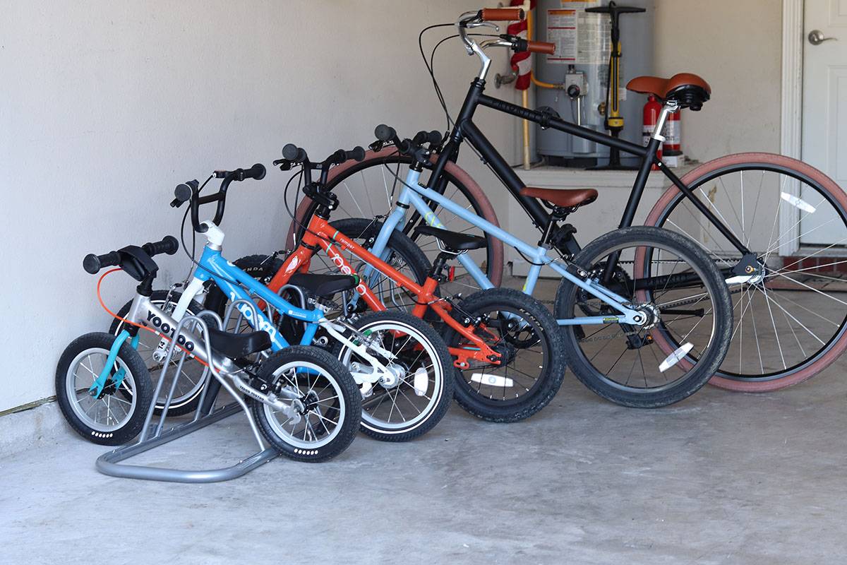 Five bikes ranging from small to large parked in a floor parking bike stand.