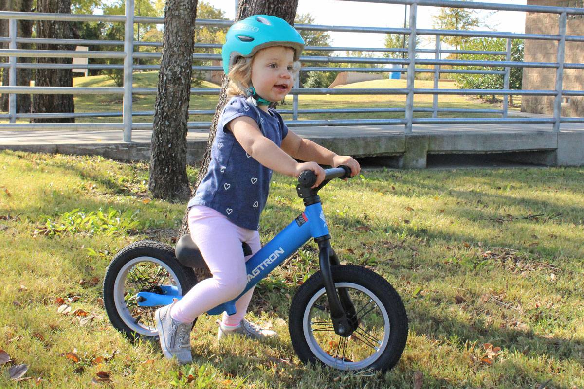 2 year old riding Swagtron K3 balance bike up ramp on grass