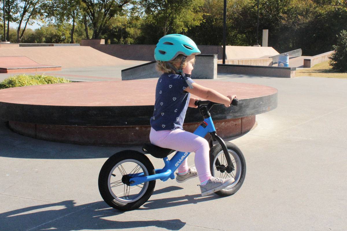 2 year old gliding on Swagtron K3 balance bike at skatepark