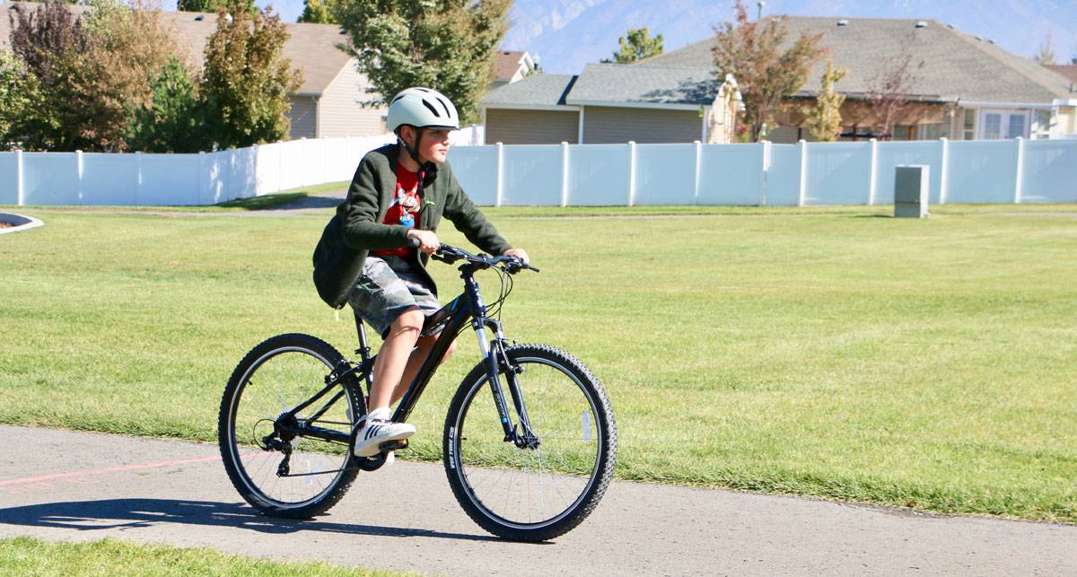 11 year old riding Raleigh Talus recreational mountain bike down paved trail
