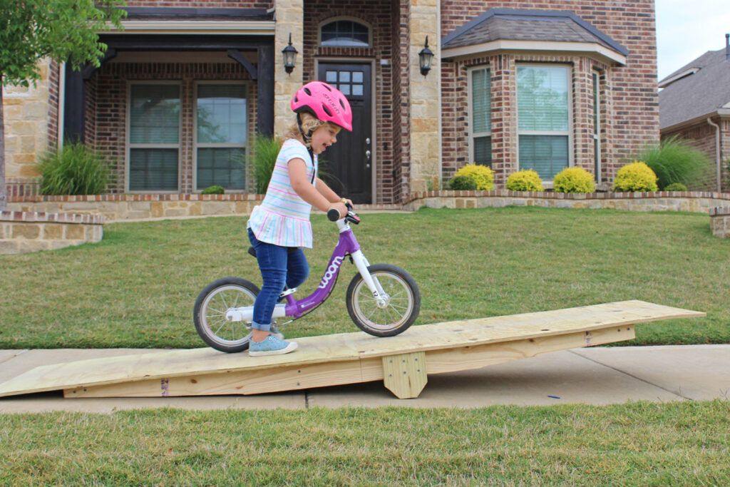 2 year old riding on a ramp with her woom 1 balance bike