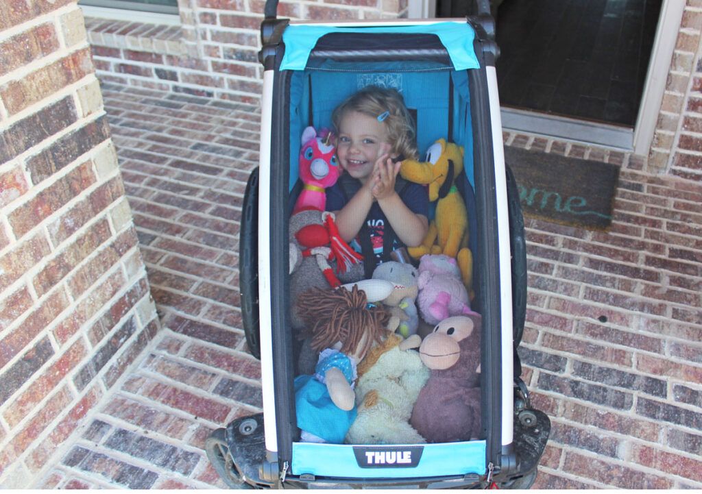 toddler zipped into the Cross with lots of stuffed animals