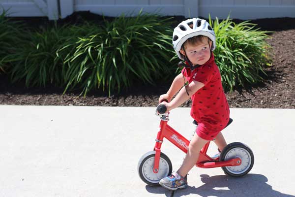 Toddler riding Toot Scoot balance bike in red