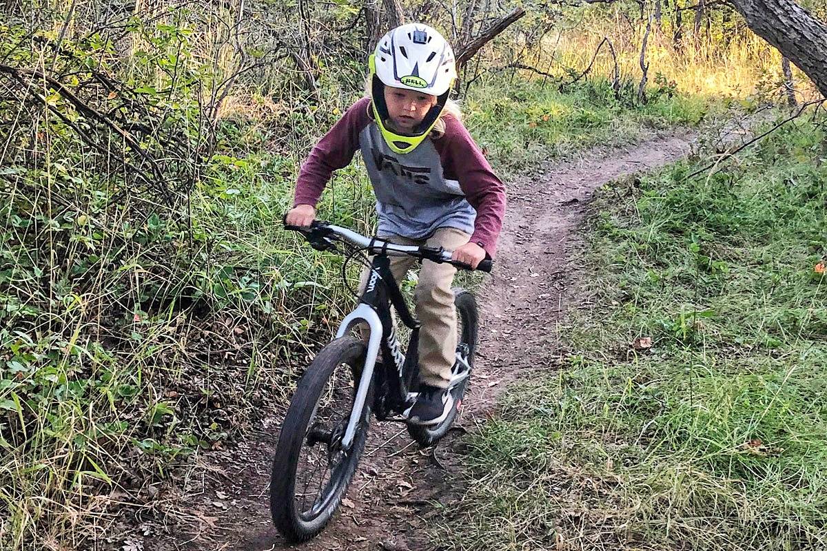 woom OFF 4 on single track with a boy wearing a full face helmet.