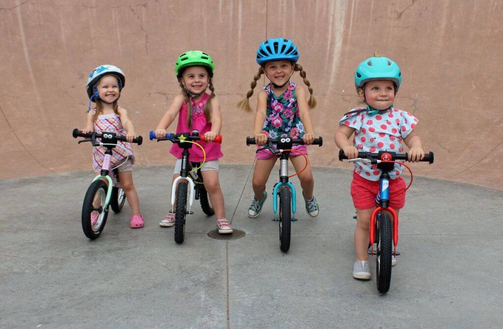 Group of four young girls on balance bikes at the skatepark