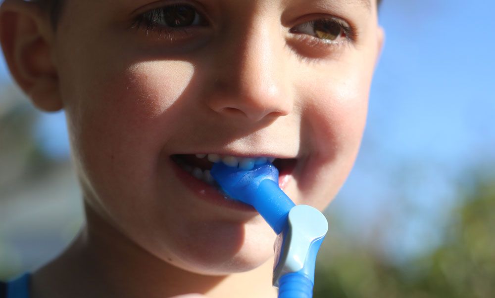boy biting the valve of the Camelbak Mini MULE kids hydration pack