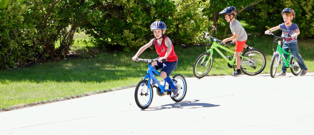 5-year-old boy riding 16" cycle kids bike in blue down the driveway